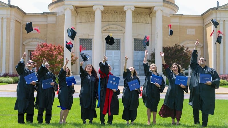 Primera promoción de graduados lanzando sus birretes al aire